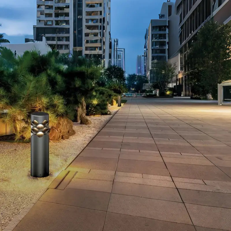 A Ripple Beam Garden Light among the gravel in the courtyard complements the green plants.