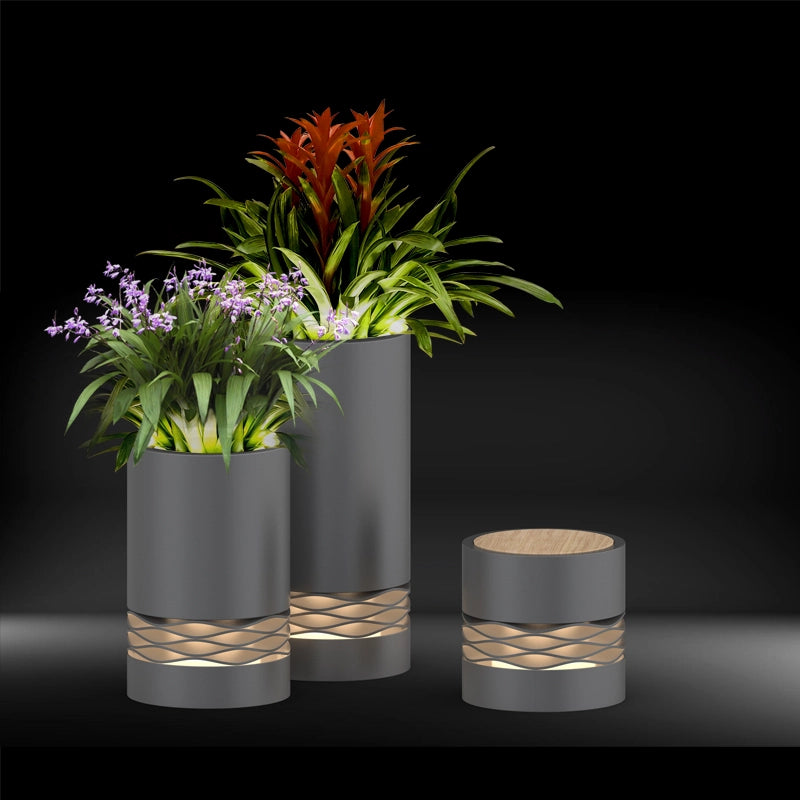 Close-up of three sizes of Outdoor Versatile Cylinder Low Light planters filled with green plants