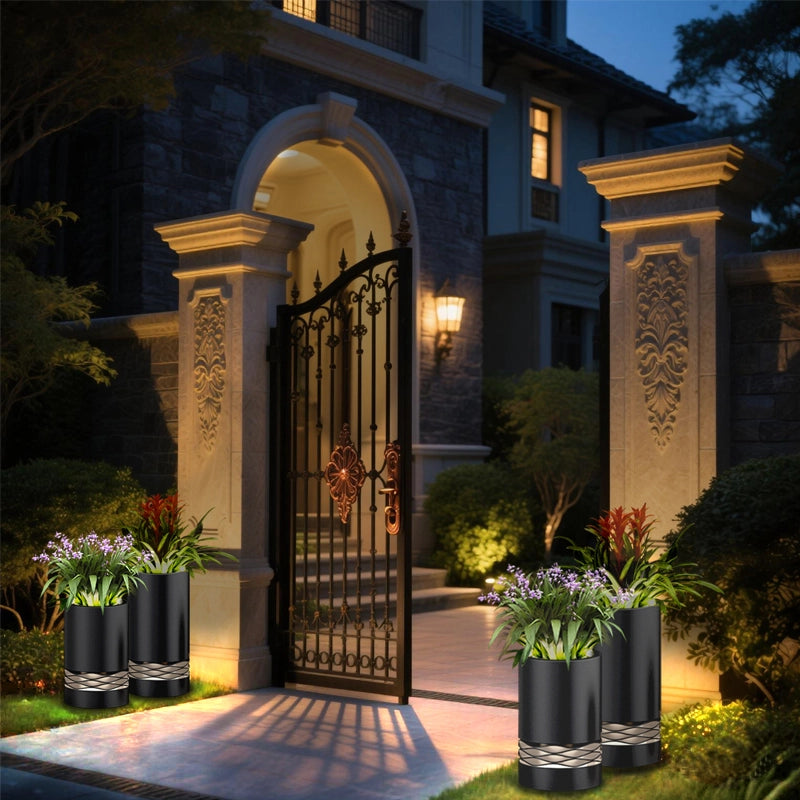 The gate of a luxurious residence at night has an exquisitely designed wrought iron gate with stone pillars with carvings on both sides. There are several pots of green plants in front of the gate, creating an elegant and solemn atmosphere. The lighting adds a sense of warmth and security.