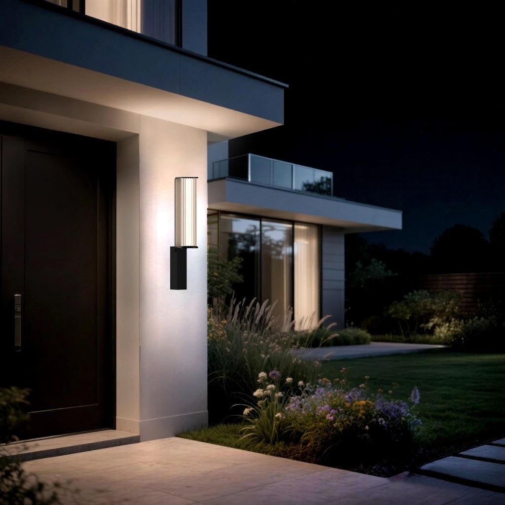 The wall lamp casts a warm glow on the exterior wall beside the lush garden, creating a cozy outdoor ambiance.