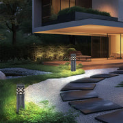 A black lawn light with a diamond pattern stands out among the gravel in the courtyard, creating an elegant scene with the flowers and plants.