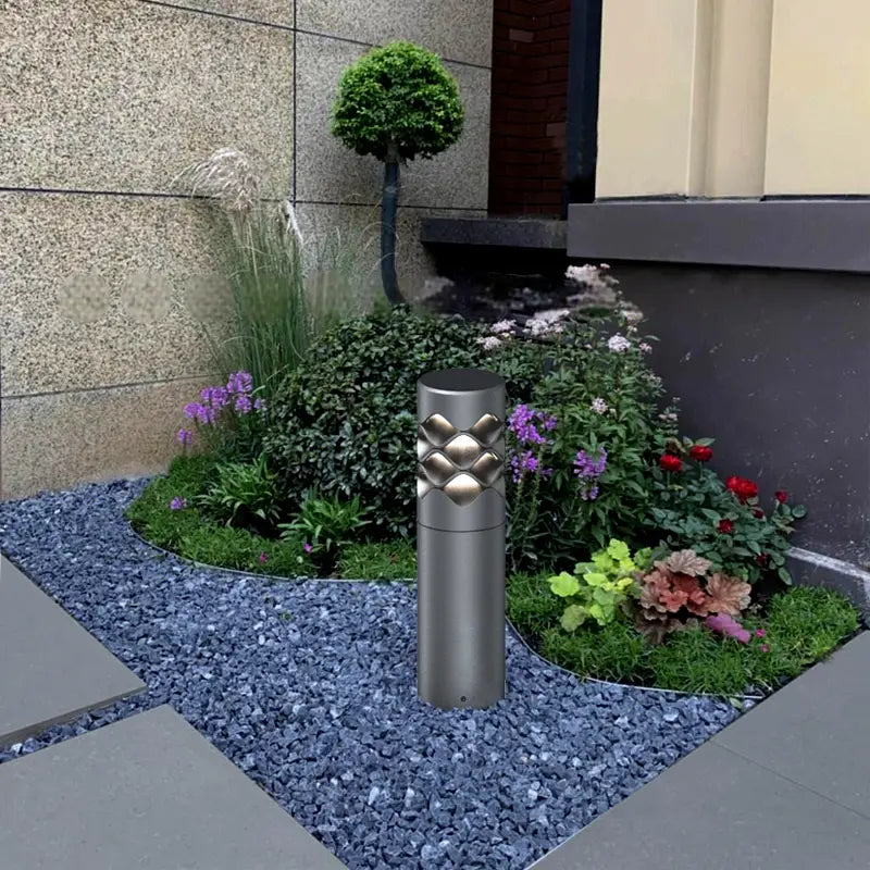 On the gravel path surrounded by flowers and plants, there is a Ripple Beam Garden Light.
