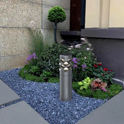On the gravel path surrounded by flowers and plants, there is a Ripple Beam Garden Light.
